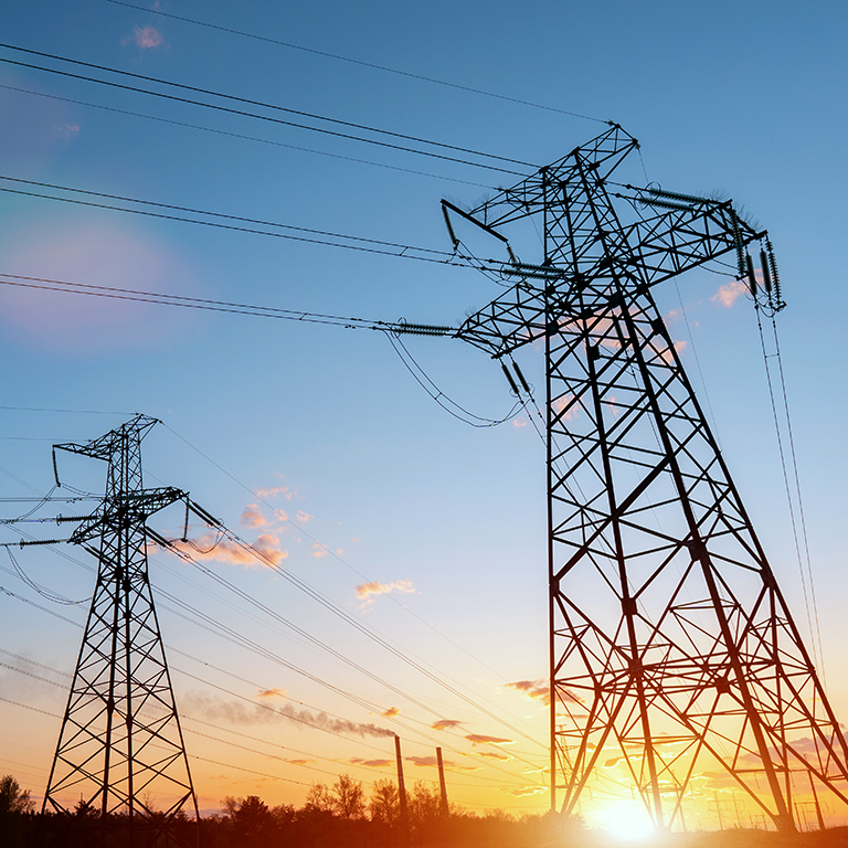 Distribution electric substation with power lines and transformers, at sunset